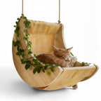 Balançoire Esprit Chat en bois naturel avec hamac en toile beige et chat roux endormi, décorée de feuilles vertes