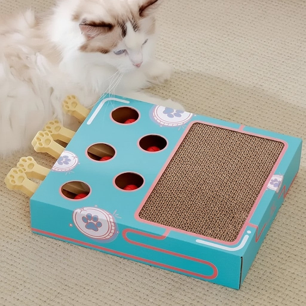 Boîte de jeu interactive pour chat Esprit Chat en carton avec griffoir et balles rouges, design bleu et rose.