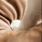 Patte de chat blanche enfoncée dans un coussin en peluche marron doux de la marque Esprit Chat