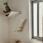 Étagère murale pour chat Esprit Chat en bois clair avec hamac en tissu blanc, installée près d'une fenêtre.