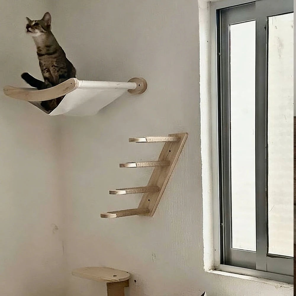 Étagère murale pour chat Esprit Chat en bois clair avec hamac en tissu blanc, installée près d'une fenêtre.