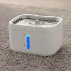 Fontaine à eau connectée blanche en plastique pour chat, avec indicateur de niveau d'eau bleu.