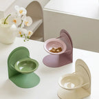 Gamelles Esprit Chat en céramique avec support réglable, disponibles en vert, rose et beige sur une table blanche.