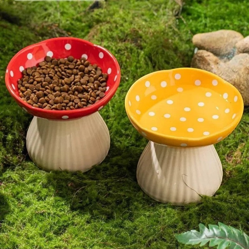 Gamelles pour chat Esprit Chat en forme de champignon rouge et jaune, en résine, posées sur de la mousse verte.
