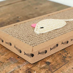Planche griffoir pour chat Esprit Chat en carton ondulé avec un jouet souris en tricot blanc et un détail rose.