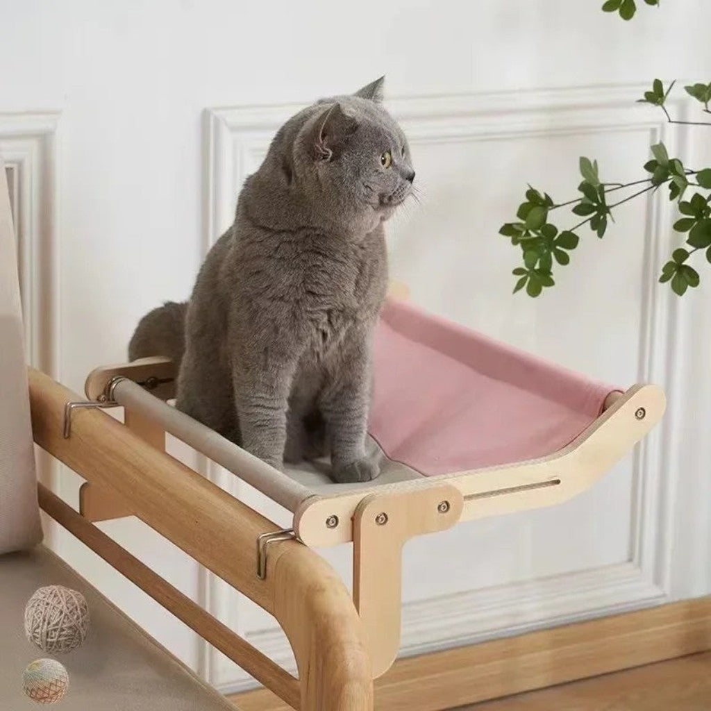 Hamac pour chat Esprit Chat en bois avec toile rose, suspendu sur un rebord de fenêtre pour le repos de l'animal.