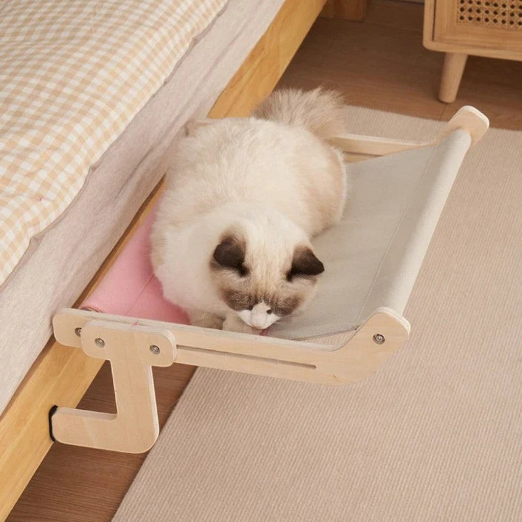 Hamac pour chat Esprit Chat en bois avec toile bicolore rose et beige fixé au bord d'un lit