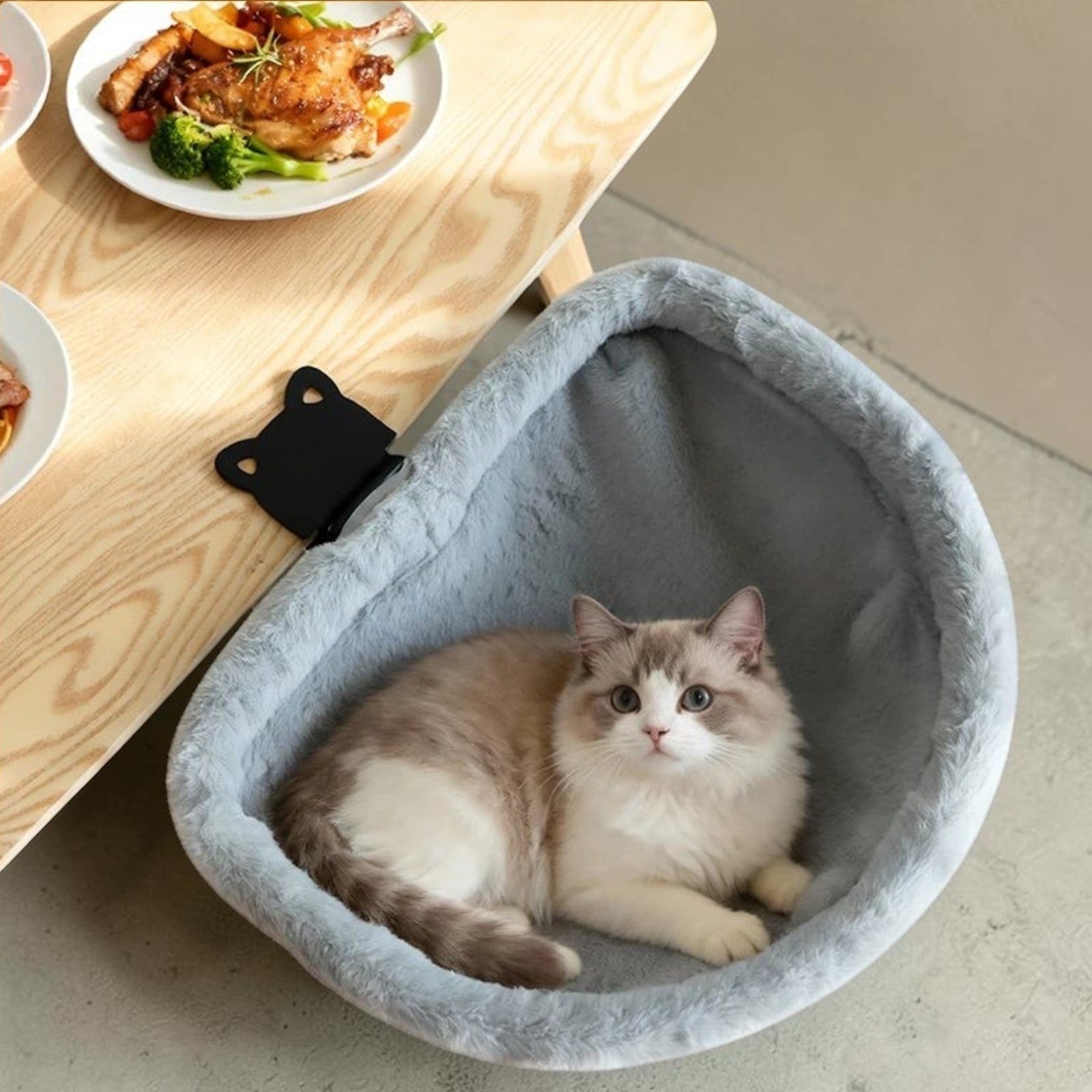 Hamac pour chat Esprit Chat en fausse fourrure grise, fixé au bord d'un bureau, avec un chat installé confortablement.