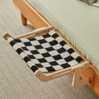 Hamac pour chat Esprit Chat en bois avec tissu à motif damier noir et blanc, suspendu au bord d'un lit.