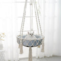 Hamac suspendu Esprit Chat en macramé blanc avec coussin bleu pour chat, style bohème chic et artisanal.