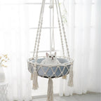 Hamac suspendu Esprit Chat en macramé blanc avec coussin bleu pour chat, style bohème chic et artisanal.