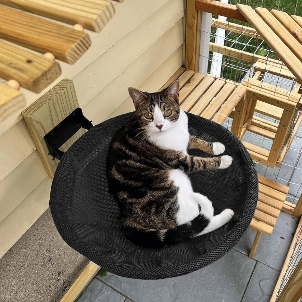 Chat tigré et blanc allongé dans un hamac mural pliable Esprit Chat en maille noire respirante sur une terrasse