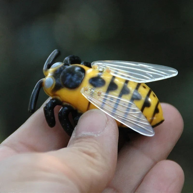 Jouet chat insecte jaune et noir en PVC, avec des ailes transparentes, tenu dans une main.