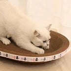 Chat blanc jouant sur un lit griffoir Esprit Chat en carton ondulé kaki avec bordure décorée de motifs de chats