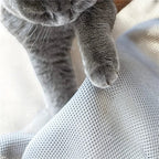 Gros plan sur une patte de chat gris touchant le tissu en maille respirante d'un lit Esprit Chat confortable