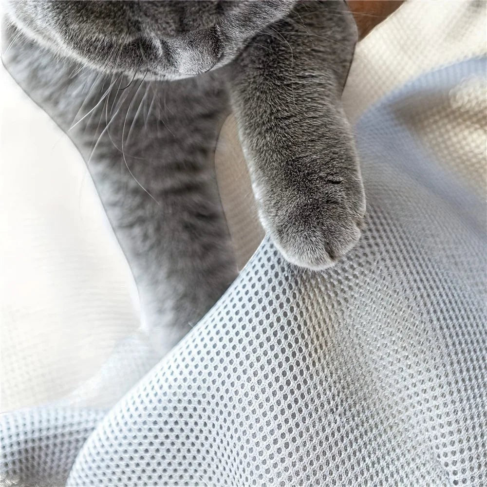 Gros plan sur une patte de chat gris touchant le tissu en maille respirante d'un lit Esprit Chat confortable