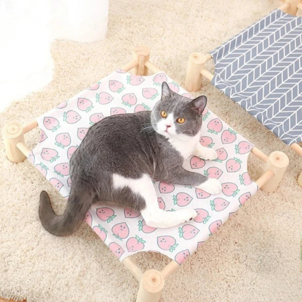 Lit surélevé Esprit Chat en bois avec hamac en toile à motif de pêches, un chat gris et blanc est allongé dessus