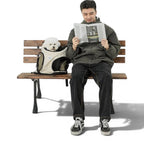 Homme assis sur un banc lisant un journal avec un petit chien blanc dans un sac de transport Esprit Chat en nylon