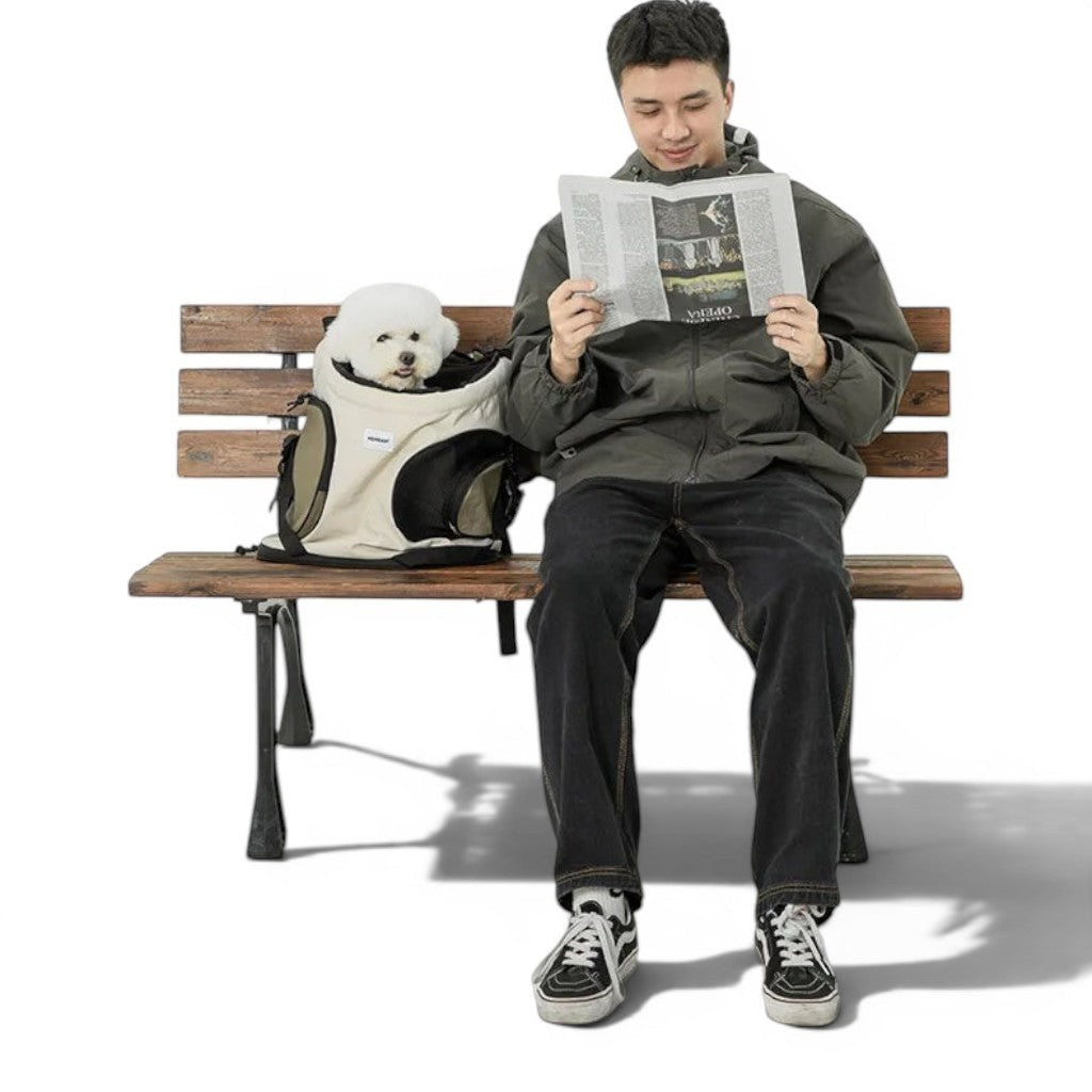 Homme assis sur un banc lisant un journal avec un petit chien blanc dans un sac de transport Esprit Chat en nylon