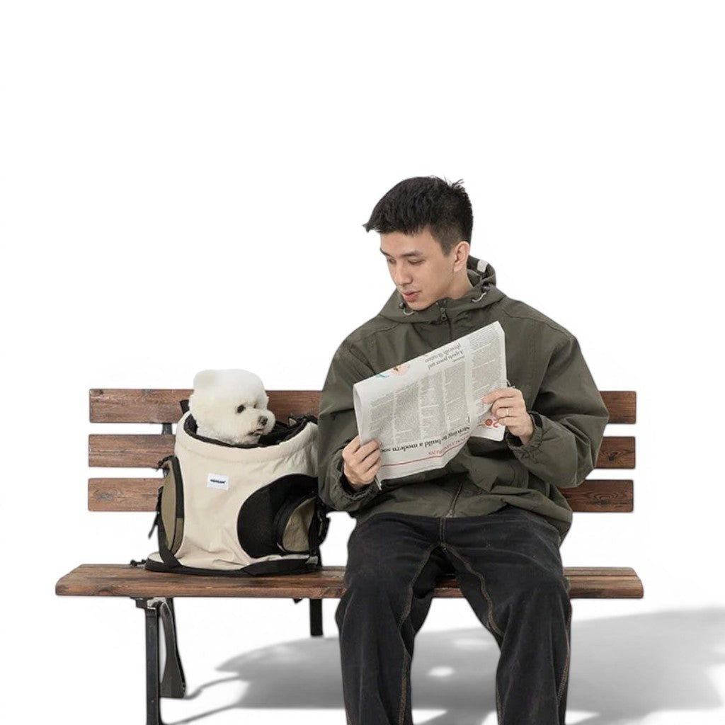 Homme assis sur un banc lisant un journal avec un chien blanc dans un sac de transport Esprit Chat en nylon beige