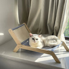 Chat blanc allongé sur un transat en bois Esprit Chat avec un tissu rayé bleu et blanc près d'une fenêtre