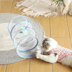 Tunnel de jeu pliable Esprit Chat en nylon bleu avec plumes pour chat, posé sur un tapis rond dans un salon.