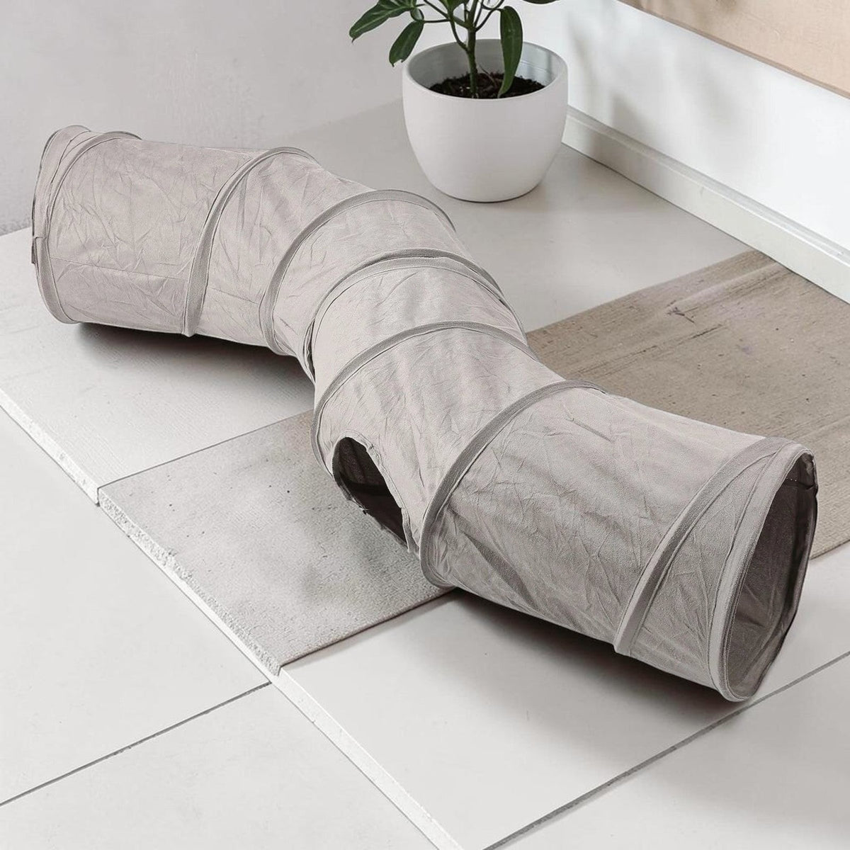 Tunnel pour chat Esprit Chat pliable en suédine grise, forme en S avec ouverture latérale pour le jeu et l'exercice.